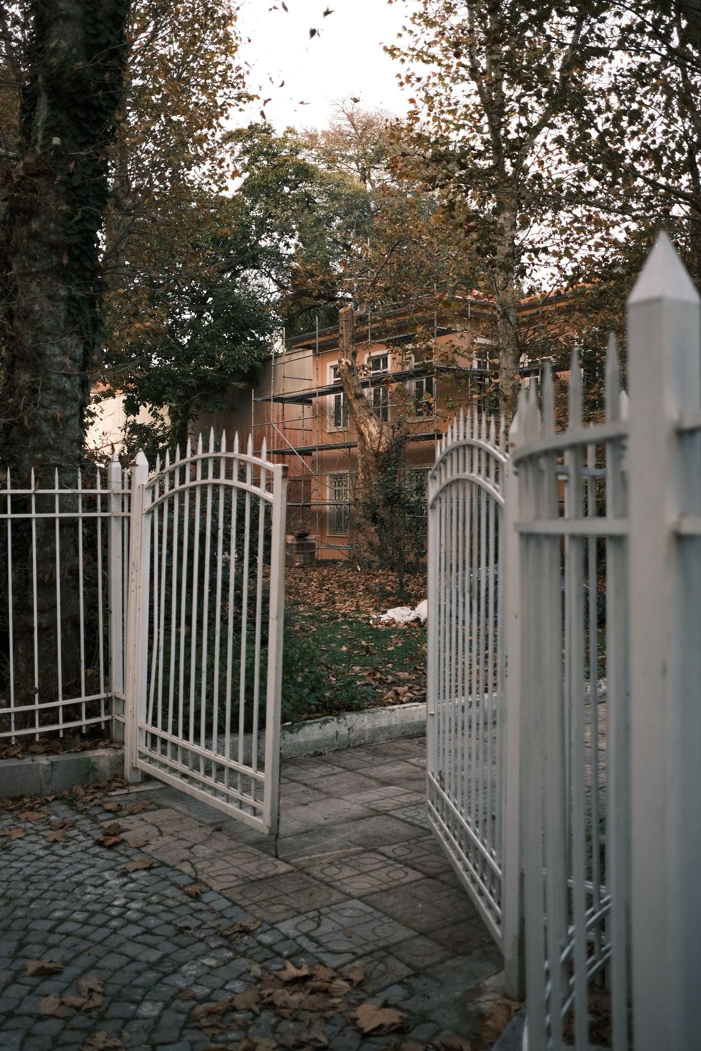 A clean white metal fence and gate beside a paved walkway