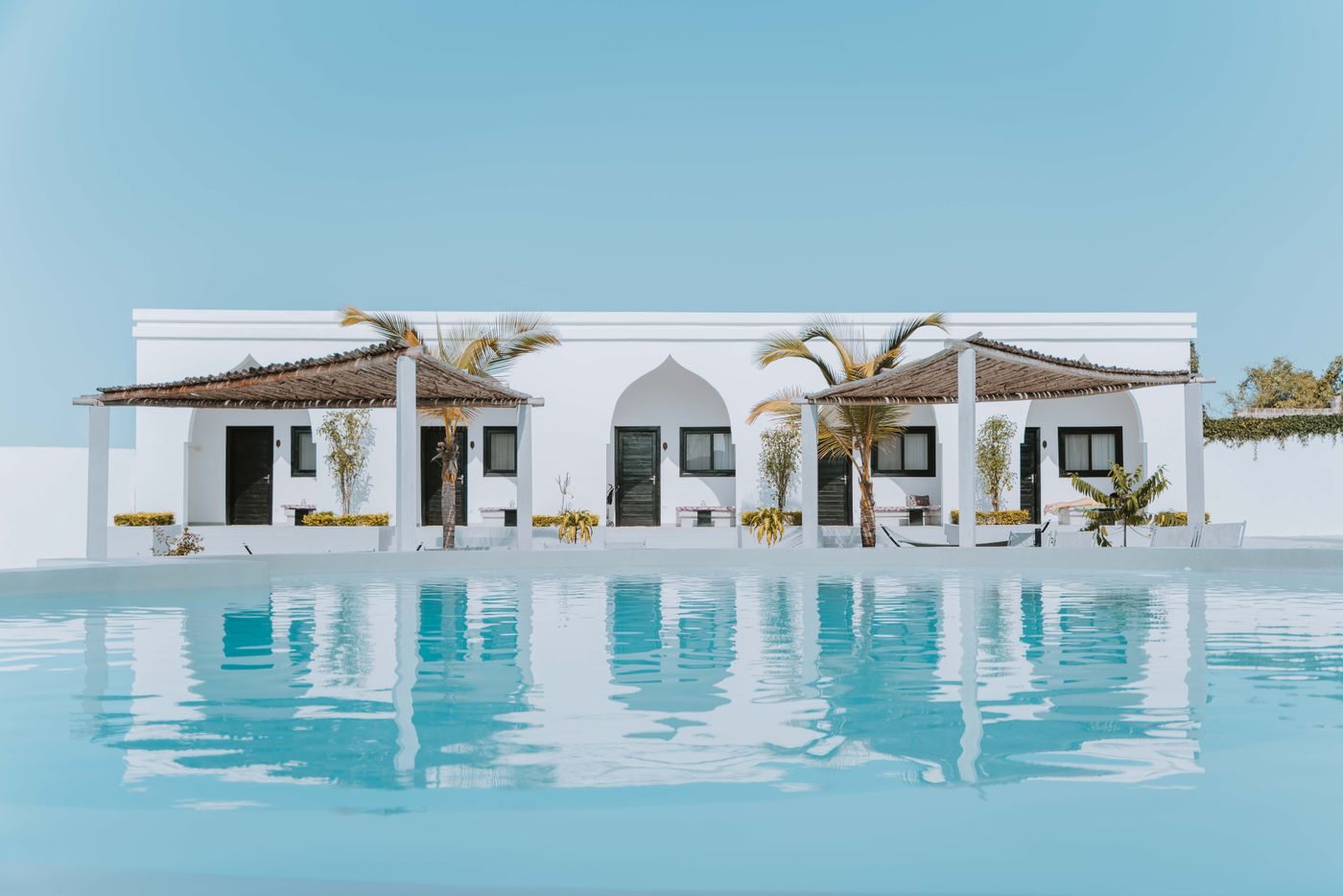 A bright, freshly washed white home exterior with a pool in South Florida